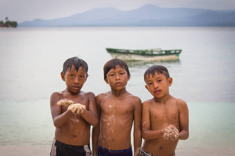 Kuna kids by the beach in San Blas with panga boat in the back